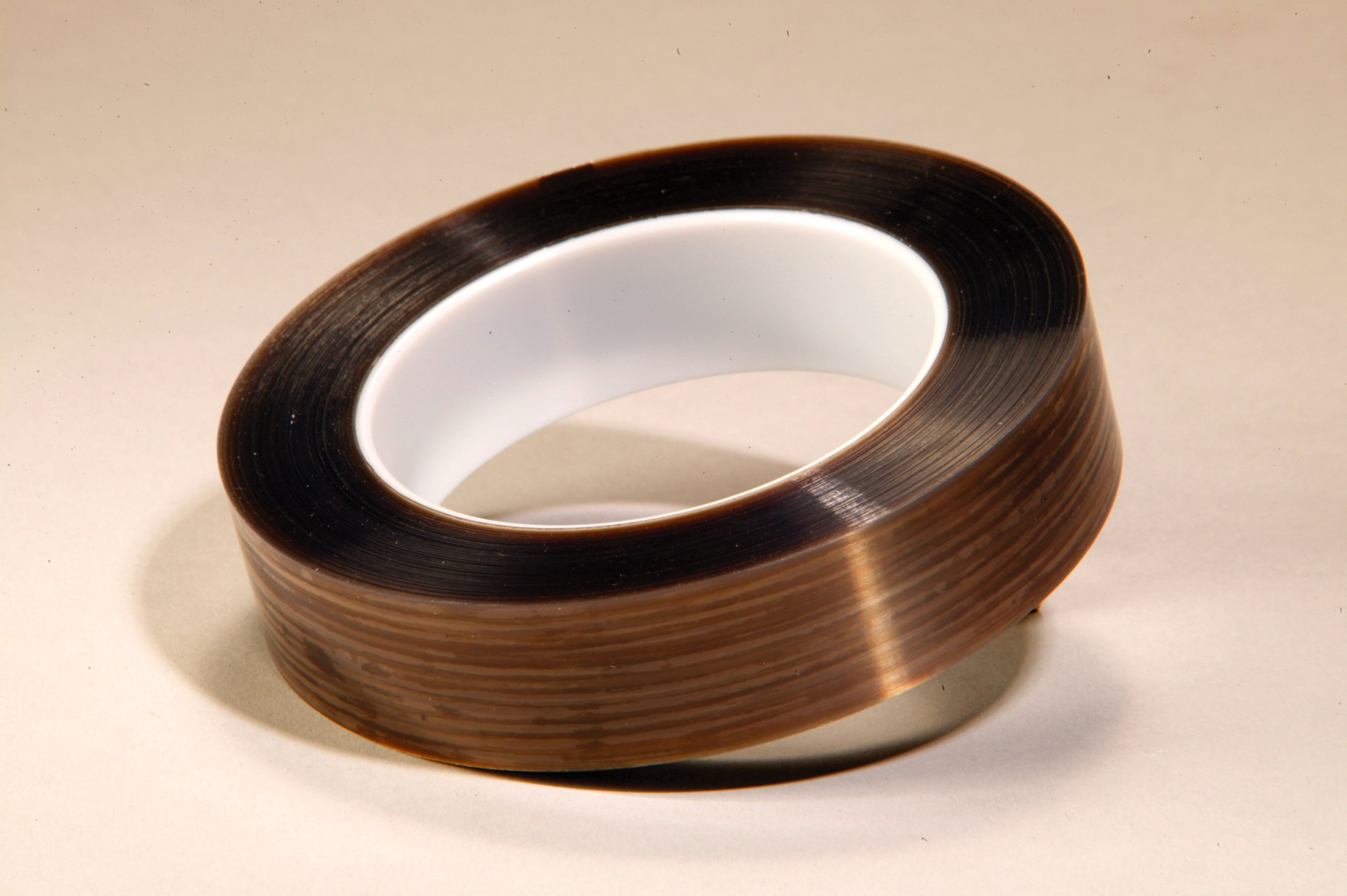 The extruded film backing resists curling when unwound from the roll and lies flatter than skived PTFE film tapes, creating a more uniform non-skid surface.